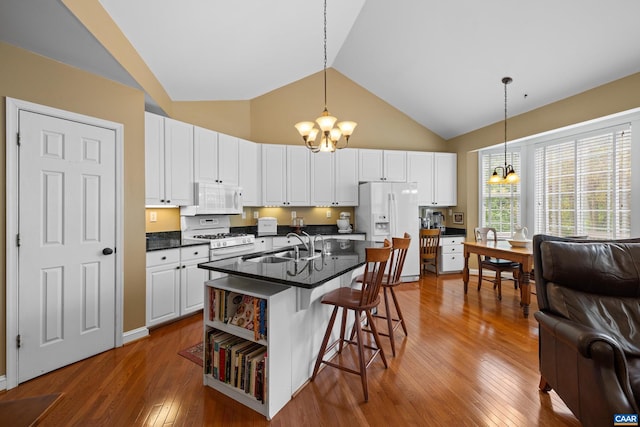 kitchen featuring an inviting chandelier, dark countertops, hardwood / wood-style floors, and white appliances
