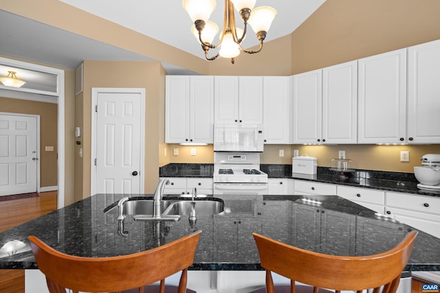 kitchen featuring an inviting chandelier, a breakfast bar, a sink, white appliances, and white cabinetry