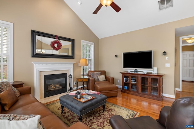 living room featuring a ceiling fan, baseboards, a fireplace with flush hearth, wood finished floors, and visible vents