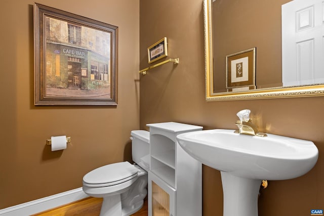 bathroom featuring toilet, baseboards, and wood finished floors