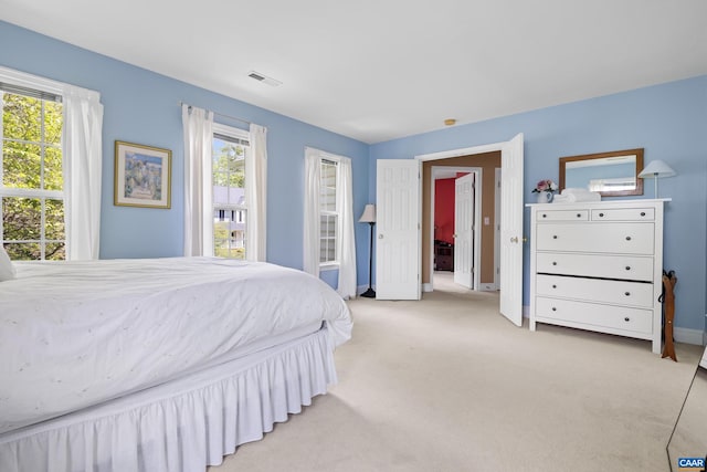bedroom with baseboards, light carpet, and visible vents