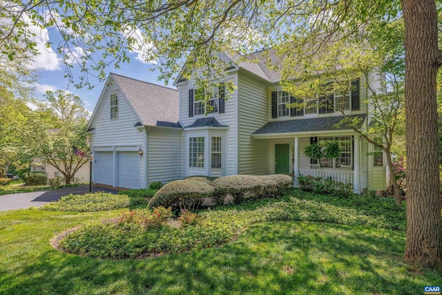 traditional home with an attached garage, a shingled roof, a front lawn, and driveway