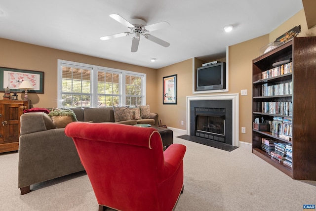 carpeted living room with baseboards, a fireplace with flush hearth, ceiling fan, and built in shelves