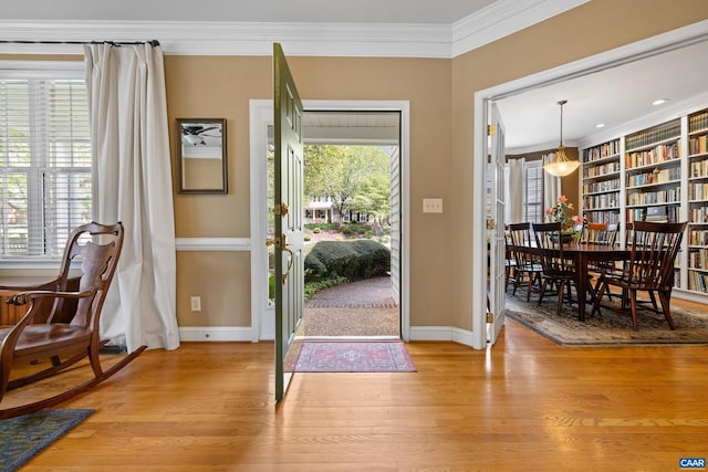 foyer with crown molding, light wood-style flooring, ceiling fan, and baseboards