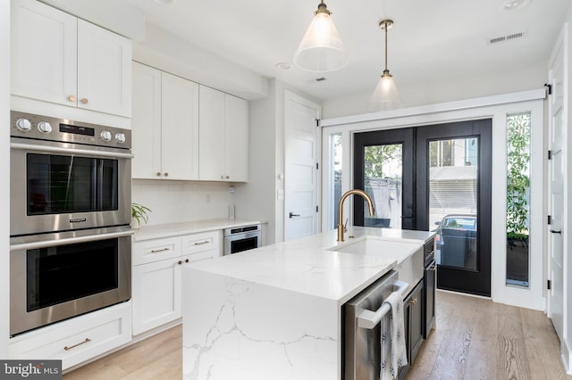 430 15th St SE, Washington, DC 20003 - kitchen featuring a sink, light wood-style flooring, stainless steel appliances, white cabinetry, and visible vents