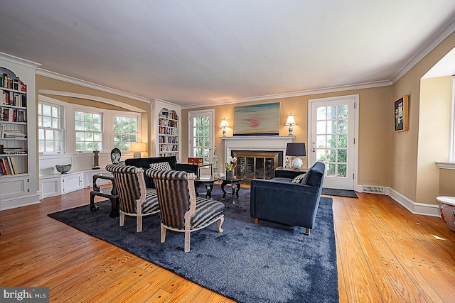 701 Argyle Rd, Wynnewood, PA 19096 - living area featuring hardwood / wood-style floors, ornamental molding, a glass covered fireplace, built in features, and healthy amount of natural light