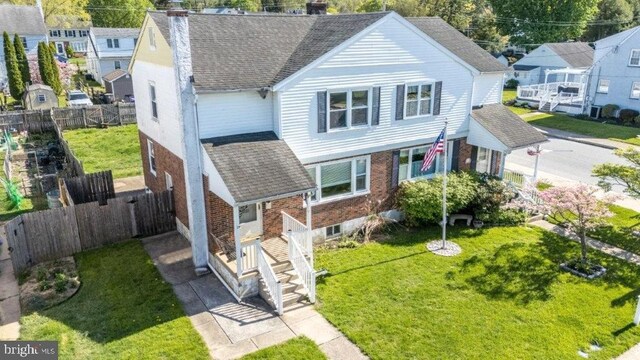 view of front of home featuring brick siding, a shingled roof, a fenced backyard, and a chimney