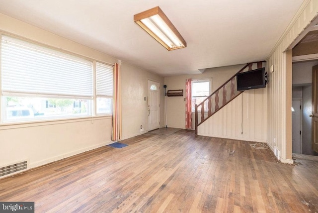 interior space with wood-type flooring, baseboards, visible vents, and stairway