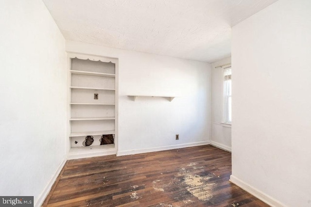 spare room featuring a textured ceiling, baseboards, and hardwood / wood-style flooring