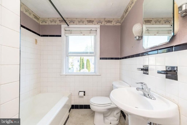 bathroom featuring a sink, toilet, and tile walls