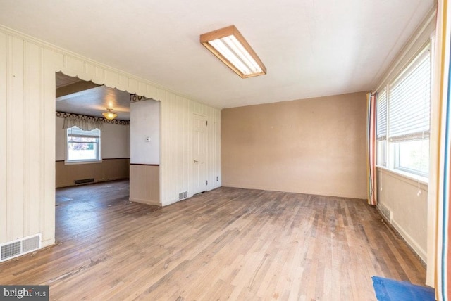 empty room featuring baseboards, wood finished floors, and visible vents