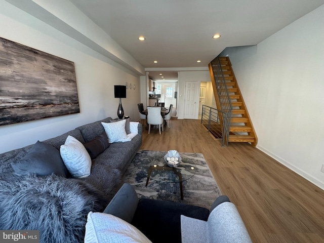 living area with recessed lighting, baseboards, stairs, and wood finished floors