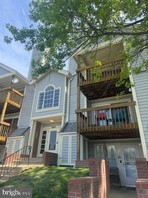 back of house with brick siding and a balcony