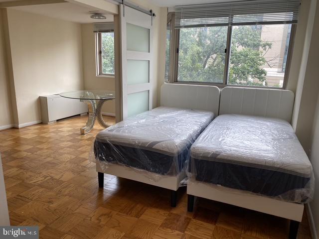 922 24th St NW Unit 517, Washington, DC 20037 - bedroom featuring a barn door, radiator heating unit, and baseboards