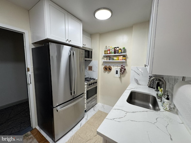 922 24th St NW Unit 517, Washington, DC 20037 - kitchen with stainless steel appliances, a sink, backsplash, white cabinetry, and light stone counters