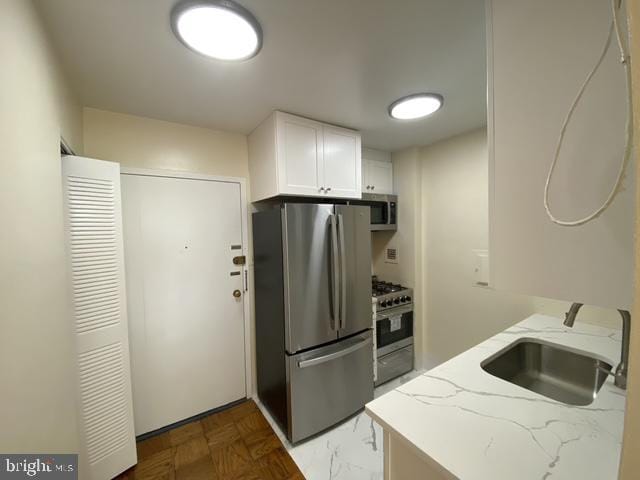 922 24th St NW Unit 517, Washington, DC 20037 - kitchen with stainless steel appliances, a sink, light stone counters, and white cabinetry