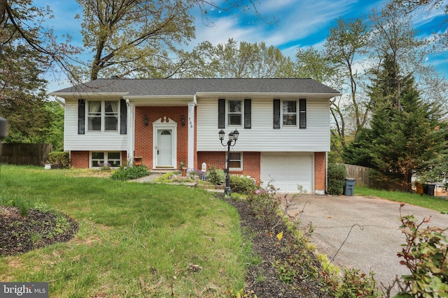raised ranch with fence, an attached garage, a front lawn, brick siding, and driveway