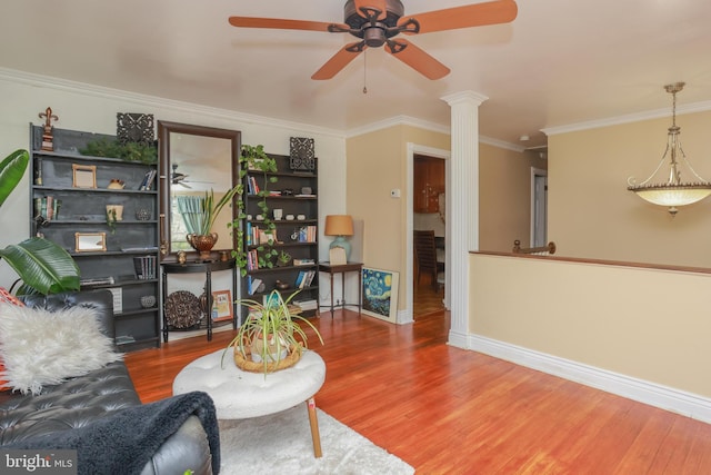 living room featuring ornamental molding, wood finished floors, baseboards, ornate columns, and a ceiling fan