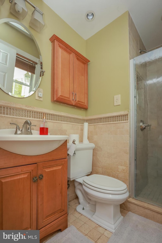 full bathroom with toilet, tile patterned floors, a wainscoted wall, tile walls, and a stall shower