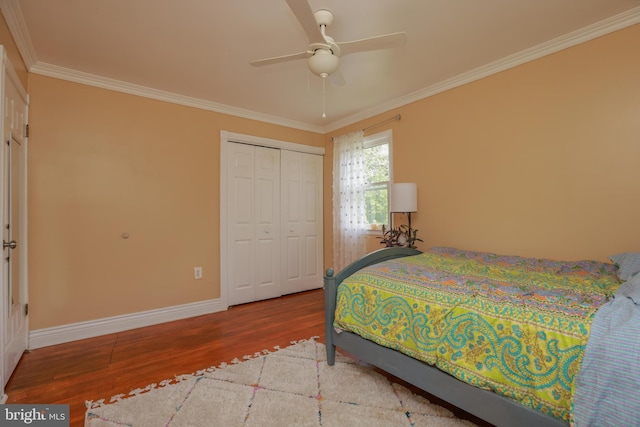 bedroom with baseboards, crown molding, wood finished floors, and a closet