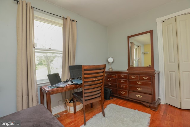 office area with visible vents, a healthy amount of sunlight, and wood finished floors