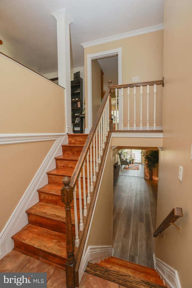stairway with crown molding and wood finished floors