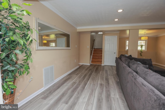 living area with visible vents, crown molding, wood finished floors, baseboards, and stairway