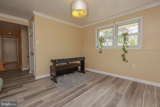 recreation room with baseboards, ornamental molding, and wood finished floors
