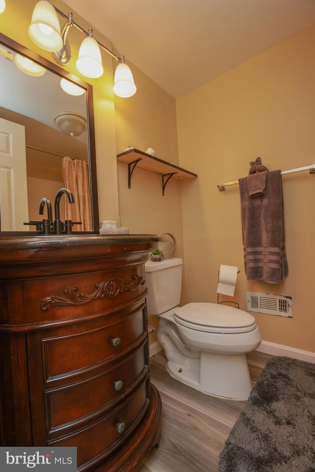 bathroom featuring vanity, baseboards, wood finished floors, and toilet