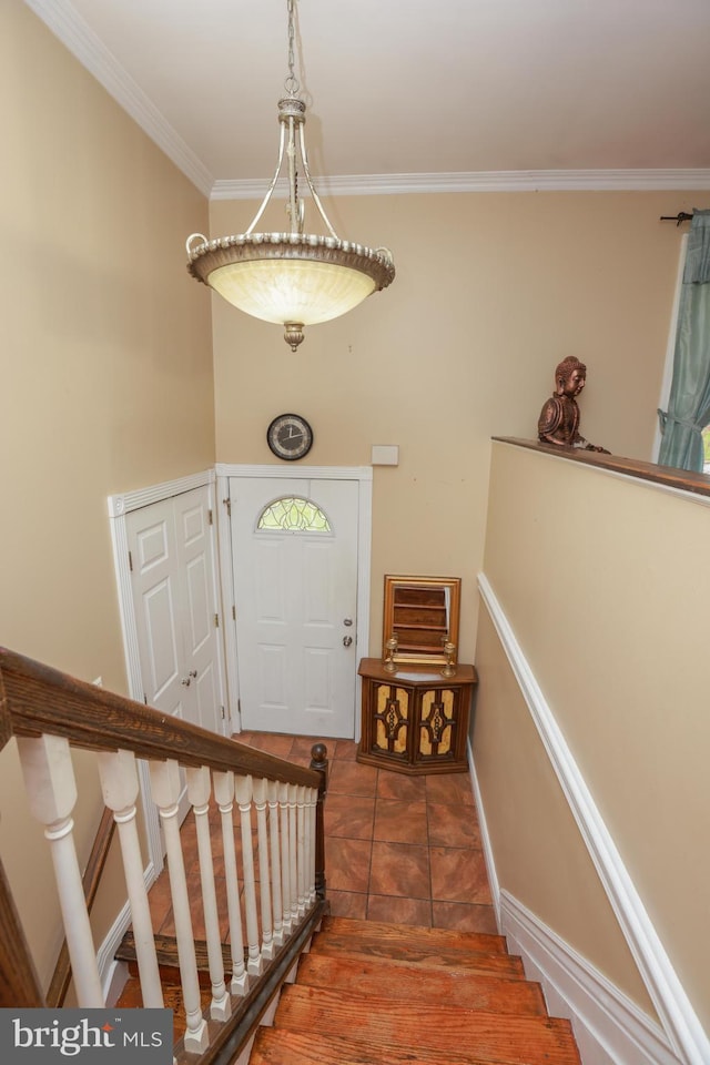 tiled foyer featuring baseboards, ornamental molding, and stairway