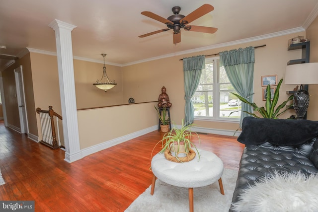 living area with ceiling fan, baseboards, decorative columns, wood finished floors, and ornamental molding