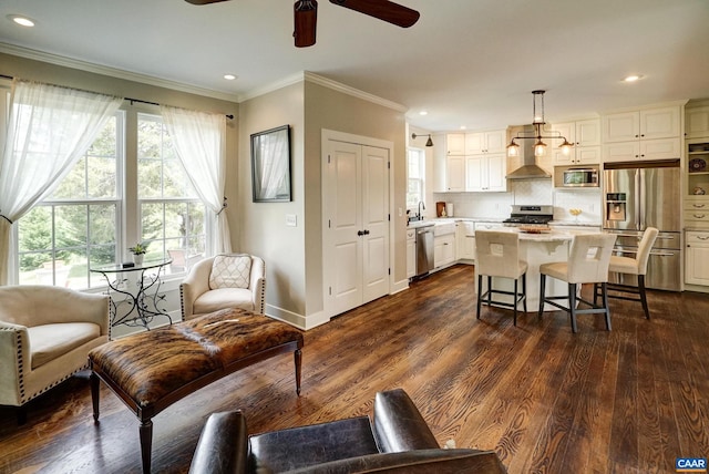 living room featuring ceiling fan, dark wood finished floors, baseboards, ornamental molding, and recessed lighting