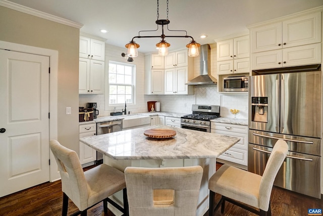 kitchen with wall chimney range hood, a kitchen breakfast bar, appliances with stainless steel finishes, dark wood-style floors, and recessed lighting