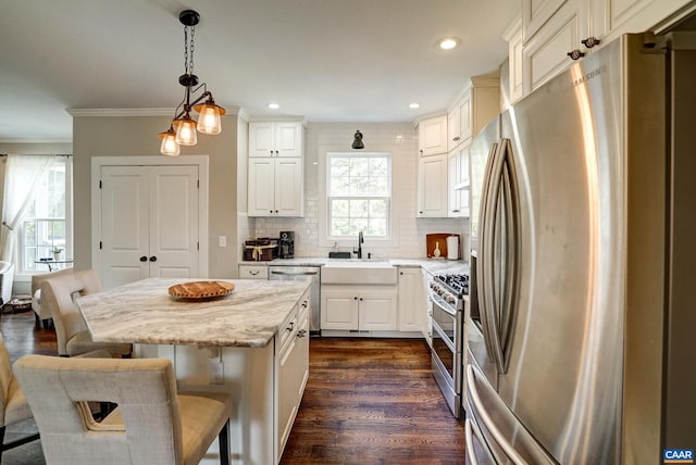 kitchen with pendant lighting, a breakfast bar, dark wood-style floors, a sink, and appliances with stainless steel finishes