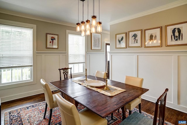 dining area featuring dark wood-style flooring, crown molding, wainscoting, an inviting chandelier, and a decorative wall