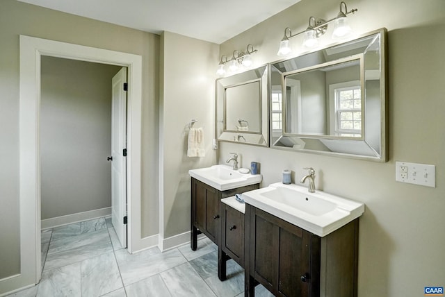 full bath featuring baseboards, a sink, marble finish floor, and two vanities