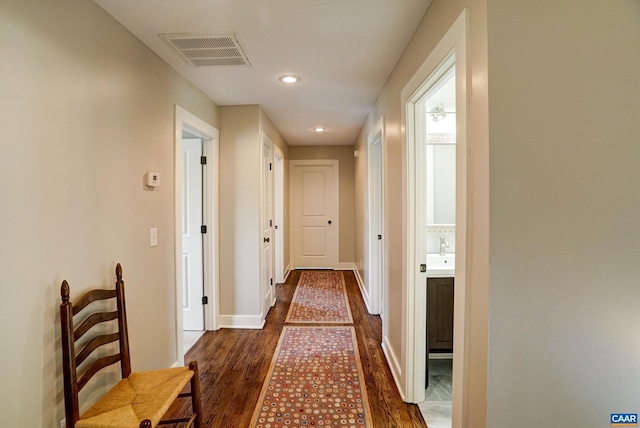hallway with a sink, recessed lighting, baseboards, visible vents, and dark wood-style floors