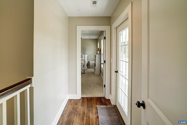 hallway featuring baseboards, a wealth of natural light, dark wood-style floors, and visible vents