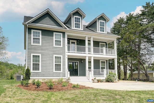 view of front of house featuring central air condition unit, a balcony, a front yard, and covered porch