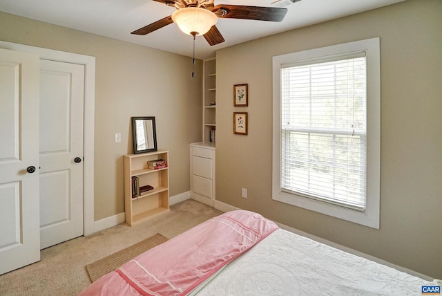 bedroom with light colored carpet, baseboards, and ceiling fan