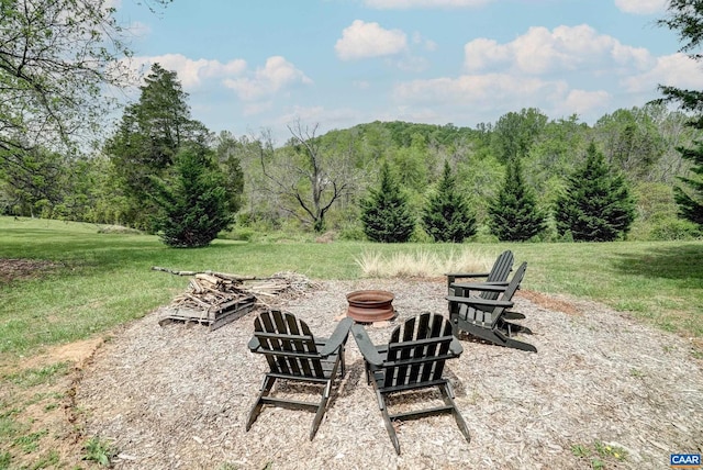 view of patio with a wooded view and a fire pit