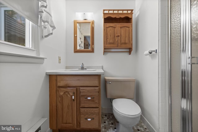 full bath featuring vanity, baseboards, a shower with shower door, and toilet