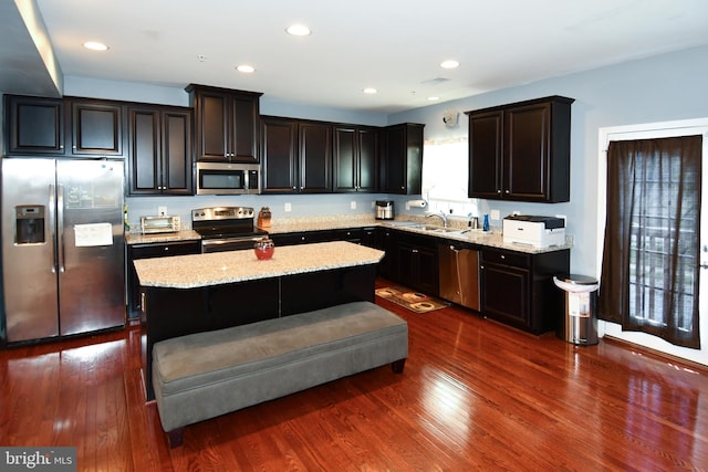 1037 Agricopia Dr, La Plata, MD 20646 - kitchen with stainless steel appliances, light stone counters, a kitchen island, a sink, and dark wood-type flooring