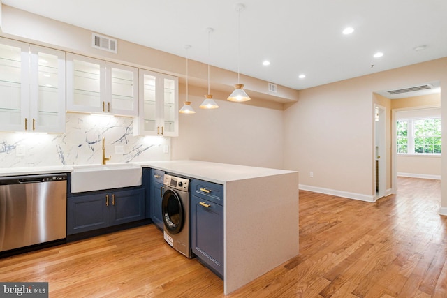 kitchen with stainless steel dishwasher, washer / dryer, a peninsula, a sink, and blue cabinets