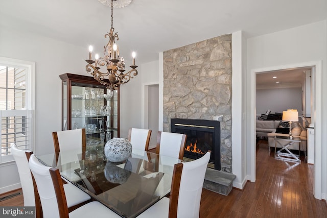 dining space featuring a fireplace, a chandelier, plenty of natural light, visible vents, and hardwood / wood-style flooring
