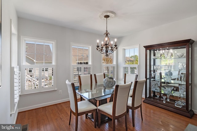 dining room featuring an inviting chandelier, wood-type flooring, baseboards, and visible vents