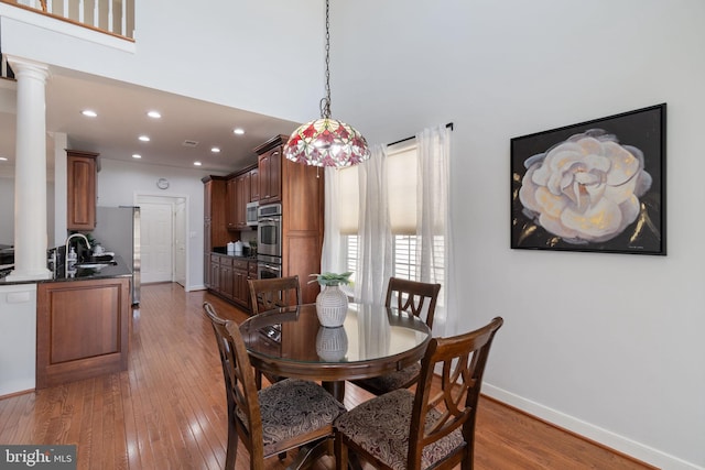 dining space featuring recessed lighting, baseboards, wood-type flooring, and ornate columns