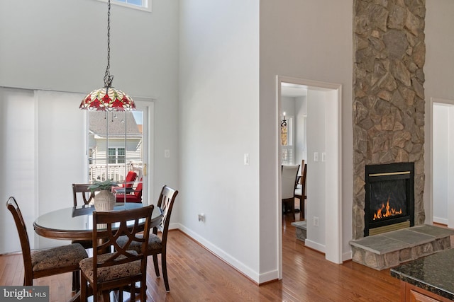 dining area with wood finished floors, a high ceiling, a wealth of natural light, and a fireplace