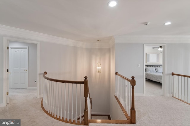 corridor featuring carpet floors, ornamental molding, baseboards, and an upstairs landing