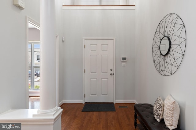 foyer with baseboards, decorative columns, wood finished floors, and visible vents